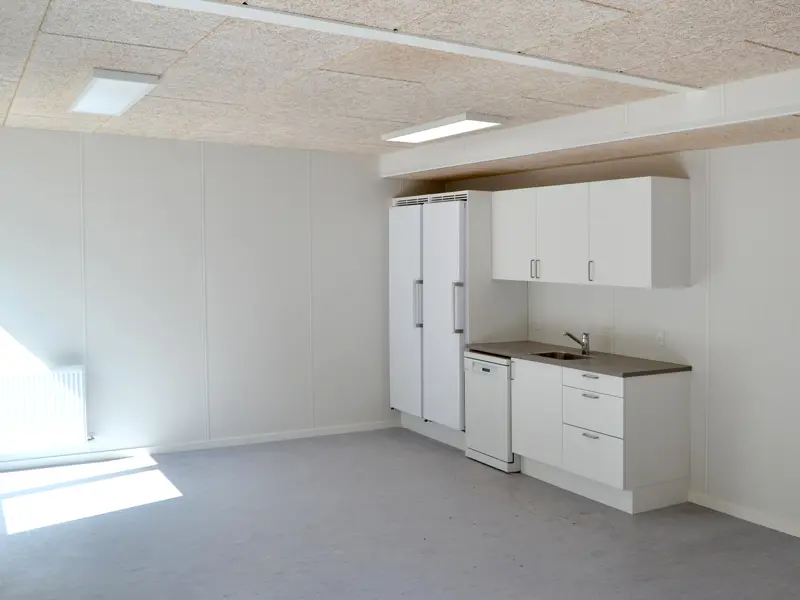 Tekøkken og personalerum. Tomt lokale med hvide vægge og sol ind af vinduerne