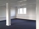 Åbent kontor med en hvid søjle i midten af rummet. Gulvtæppe, hvide vægge og lofter.