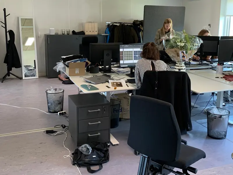 Kontorborde med computerskærme, medarbejdere som arbejder