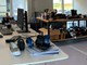 Fodboldstøvler og kondisko placeret forrest på kontorbordet, hvor der også står en computer. I baggrunden er der fremvisningsborde placeret midt i rummet med en masse forskellige sko.